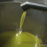 Demonstration of pouring olive oil into a metal pot, explaining the process for making olive oil.