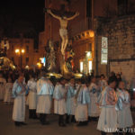 A group of people in white robes celebrating Easter in Italy, standing in front of a statue of Jesus.