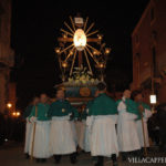 A group of priests participating in the Easter procession, carrying a cross through the streets of Italy.