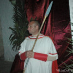 A man in a white robe holding a long stick during an Easter procession in Italy.