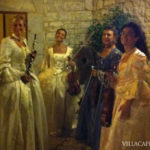 A group of women dressed in medieval costumes are posing for a picture while enjoying Italian folk music.