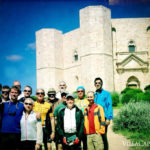 A group of people on an Italian bike tour posing in front of a castle.